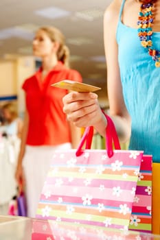Close-up of womans hand holding plastic card while going shopping in the mall
