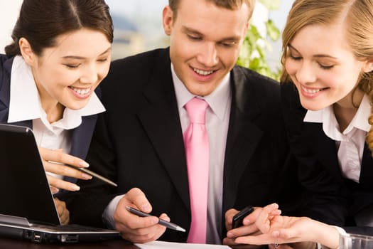 Photo of young businessman between two smart women pointing at document during meeting