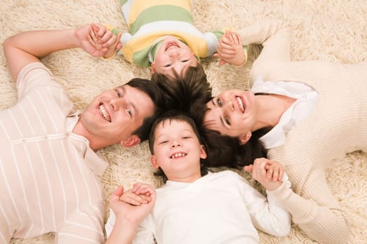 Above view of cheerful parents with their two sons holding by hands and smiling at camera