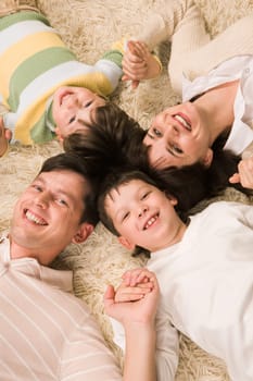 Above view of cheerful couple with their two sons holding by hands and smiling at camera
