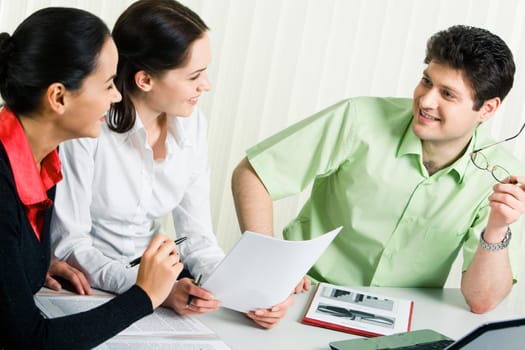 Photo of confident businessman voicing his working ideas while two smiling ladies listening to him attentively