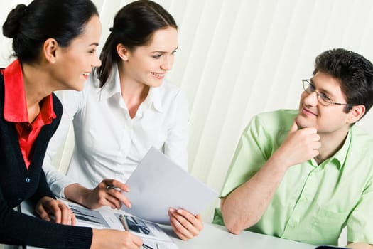 Portrait of three colleagues sitting in the office and sharing their ideas about business project