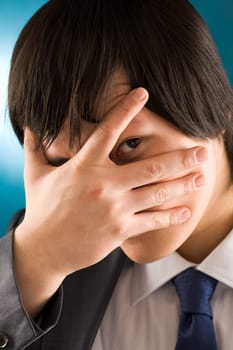 Portrait of young businessman looking at camera from behind his hand