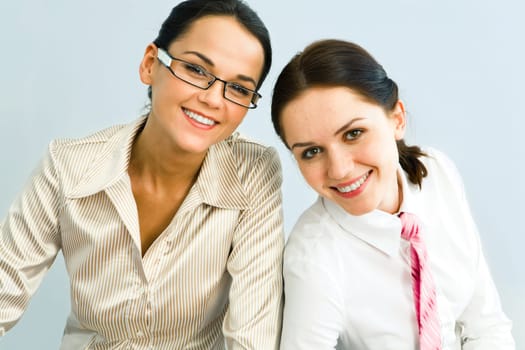 Portrait of two pretty women looking at camera on a blue background