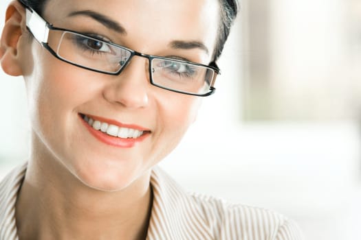 Close-up of face of pretty businesswoman with glasses looking at camera