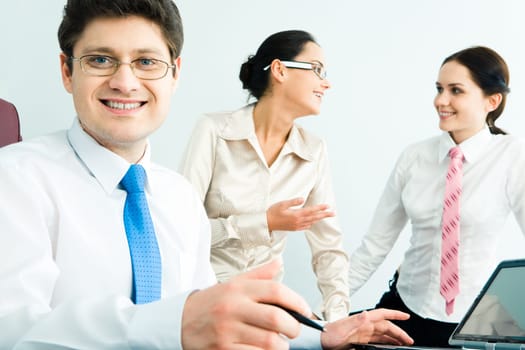 Portrait of successful businessman with glasses on the background of talking women