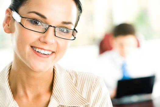 Portrait of cheerful woman looking at camera on the background of working man