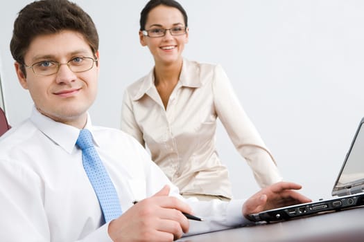 Photo of smiling confident boss looking at camera with woman sitting near by