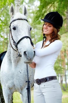 Image of happy female grooming purebred horse outdoors
