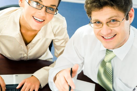 Close-up of smiling business partners at work looking upwards at camera