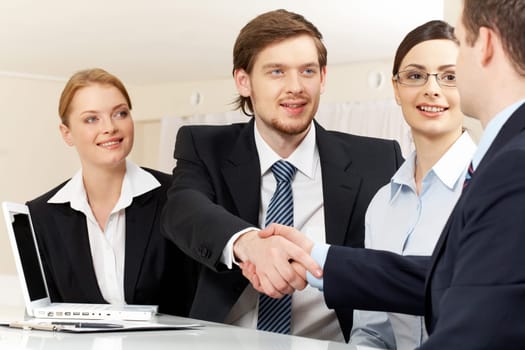 Photo of successful business partners handshaking after striking deal with pretty employees near by