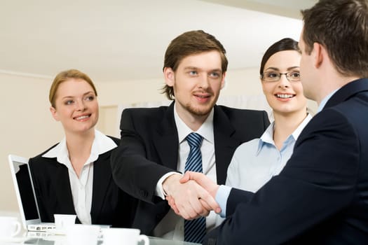 Photo of successful business partners handshaking after striking deal with pretty employees near by