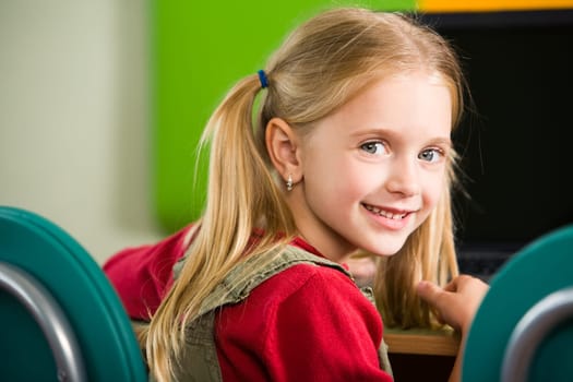Portrait of smiling girl looking at camera while sitting at her place