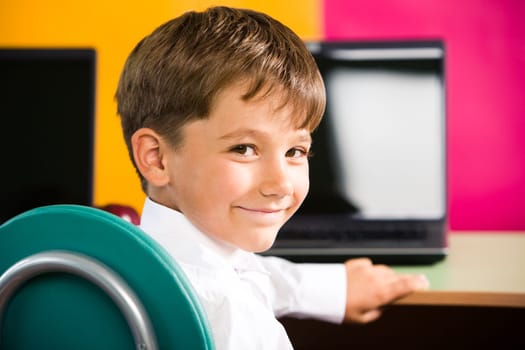 Image of cute pupil turning his head and looking at camera with smile