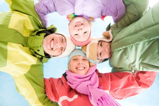 Below angle of happy family embracing and looking at camera