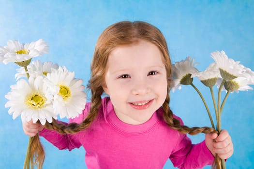 Image of lovely girl with white flowers in both hands looking at camera and smiling