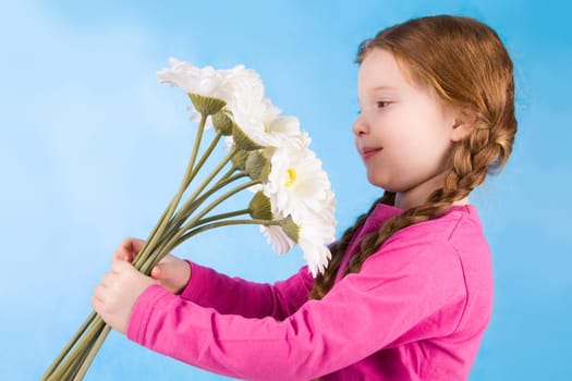 Photo of little girl smelling spring flowers and enjoying them