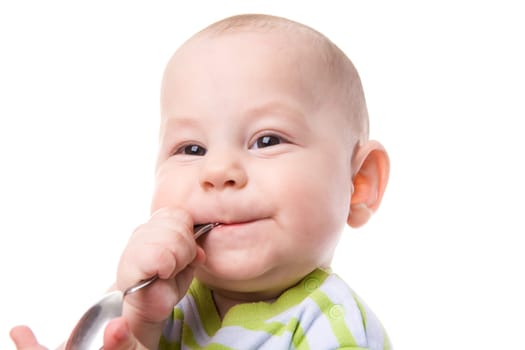 Portrait of cute boy with spoon in mouth and smile on his face