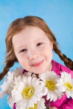 Portrait of adorable child with chamomile bouquet looking at camera and smiling