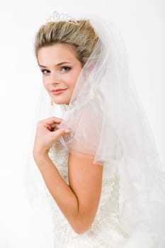Portrait of pretty bride wearing veil and touching it while looking at camera