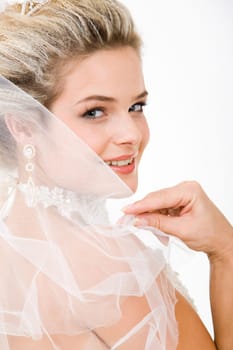 Photo of happy bride touching her veil and looking at camera with smile