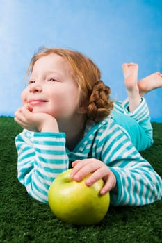 Photo of relaxing girl lying on green grass with apple in hand
