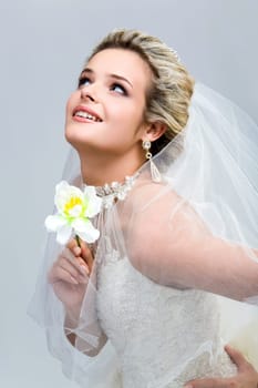 Portrait of modern bride with orchid in hand looking upwards