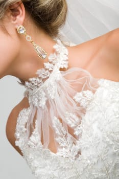 Close-up of bridal neck and chest framed by white wedlock lace and with elegant earring in ear