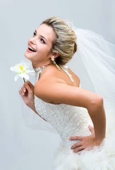 Portrait of joyful bride holding flower in hand and laughing while looking upwards