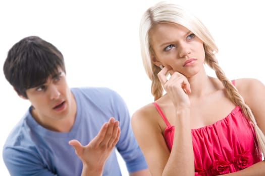 Sad woman with pensive expression touching her face on background of displeased man