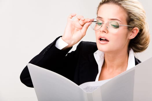 Portrait of smart businesswoman in glasses looking at document in her hand and reading it