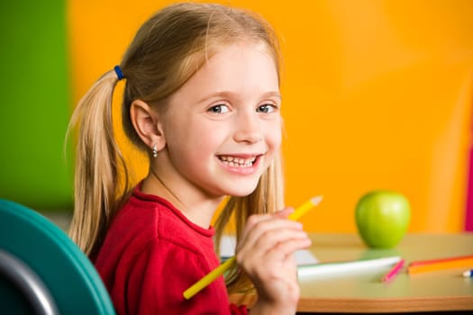Portrait of diligent schoolgirl with pencil looking at camera during lesson