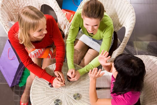 Photo of happy girls chatting in cafe after shopping