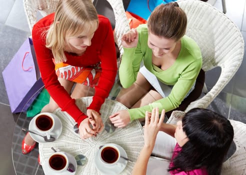 Above view of three young women communicating in cafe