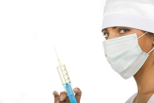 Nurse in mask holding syringe in hand while checking volume of medicine in it