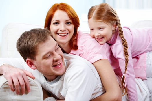 Portrait of happy parents and their daughter having fun at home