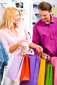 Portrait of cheerful woman showing presents to her boyfriend in the store