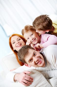 Portrait of happy parents and their children lying on the sofa