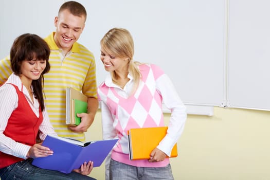 Portrait of smart students looking at textbook in girls hands and reading it