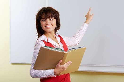 Portrait of clever girl standing near whiteboard and pointing at it