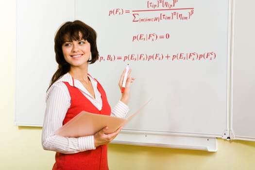 Image of attractive teacher writing formula on whiteboard during lesson