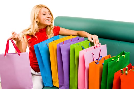 Portrait of smiling blonde sitting on sofa with several colorful shoppingbags