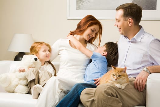Photo of cute boy embracing his pretty mother surrounded by playful daughter and their father