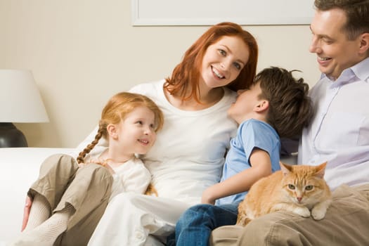 Portrait of happy parents and their children sitting on the sofa with red cat on mans knees