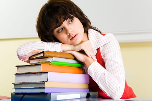 Photo of attractive woman putting her head onto stack of books and looking aside