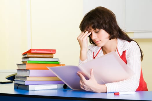 Photo of pensive teacher sitting at the desk and refreshing study material before lesson