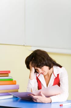 Image of tired student sitting at desk before textbook and looking into it with exhausted expression