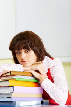 Photo of attractive woman putting her head onto stack of books and looking aside