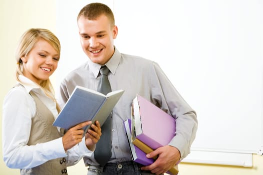 Portrait of two successful students looking into notebook together with smiles