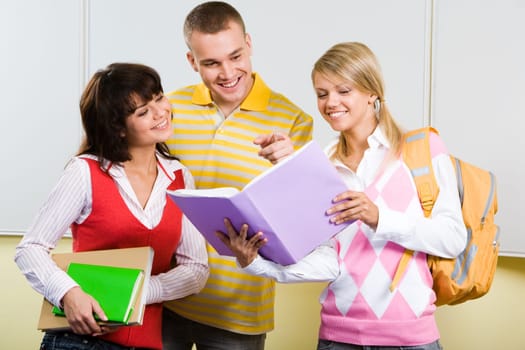 Portrait of three friends standing in classroom and discussing lessons